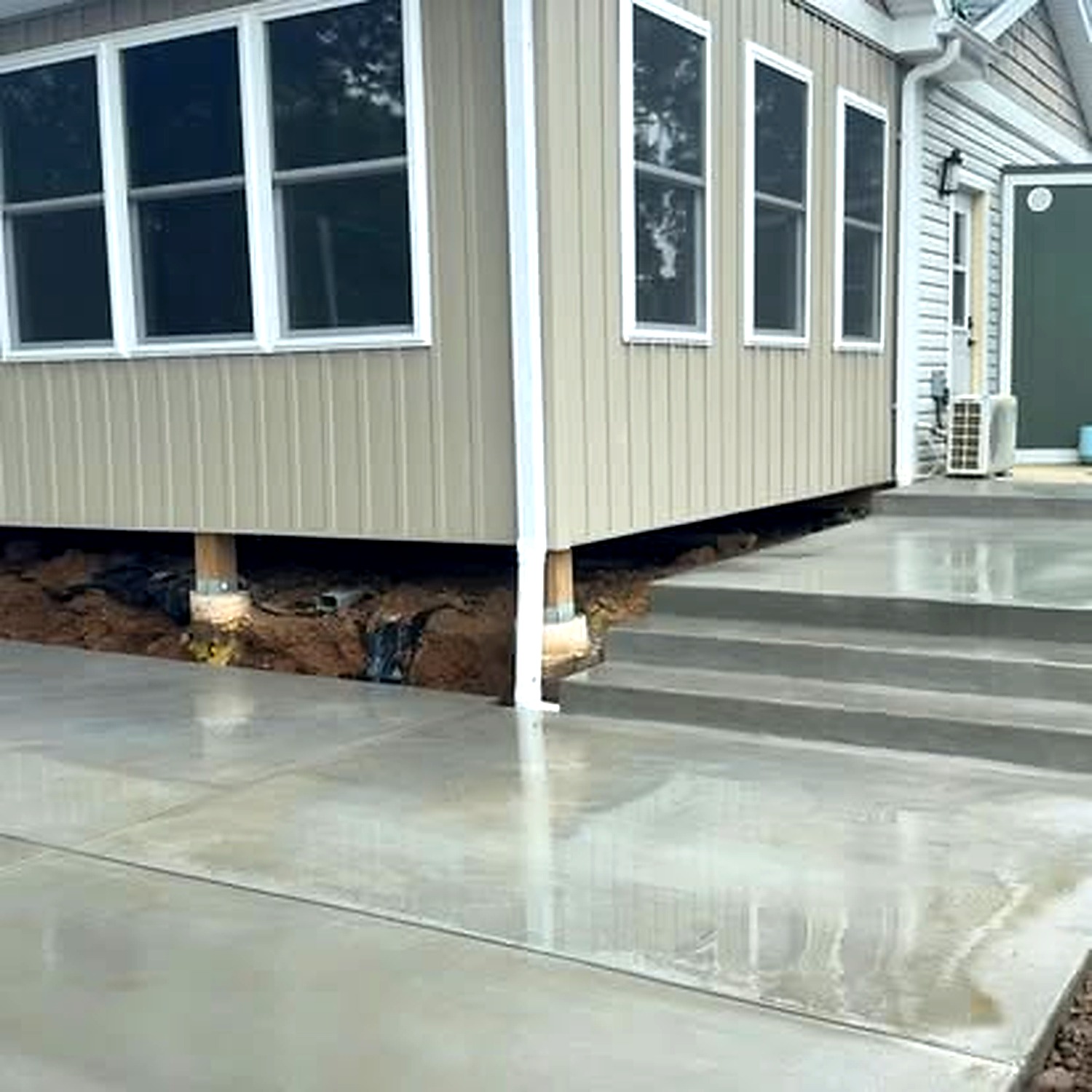 Fresh concrete driveway wrapping around sunroom — True Form Concrete