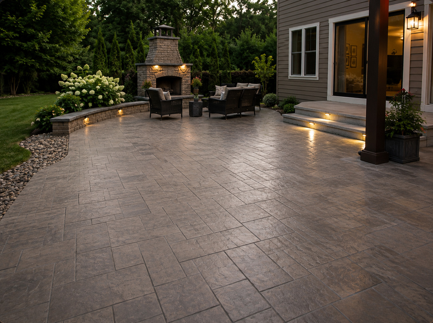 Stamped concrete patio with stone fireplace at dusk — True Form Concrete